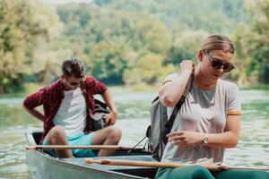 Couple adventurous explorer friends are canoeing in a wild river surrounded by the beautiful nature photo