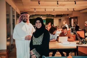 retrato foto de árabe líder empresario con musulmán hijab mujer que se discute negocio proyectos mientras utilizando tabletas y teléfono inteligente en moderno vaso oficina