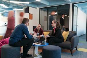 Multiethnic startup business team on meeting in a modern bright open space coworking office. Brainstorming, working on laptop. Group of coworkers walking around in motion blur. photo