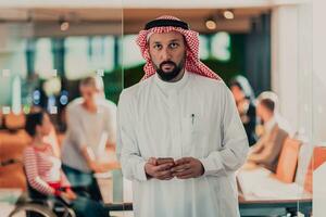 Middle eastern Arab businessman in the office speaking on smartphone in front of his team photo