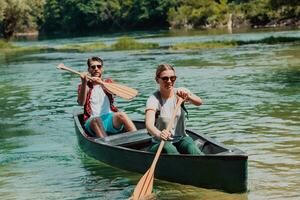 Couple adventurous explorer friends are canoeing in a wild river surrounded by the beautiful nature photo