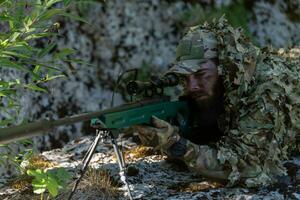 Army soldier holding sniper rifle with scope and aiming in forest. War, army, technology and people concept photo