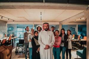 un diverso grupo de exitoso negocio personas en un moderno vaso oficina estar juntos a el parte superior con su árabe líder director foto