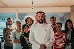 un diverso grupo de exitoso negocio personas en un moderno vaso oficina estar juntos a el parte superior con su árabe líder director foto