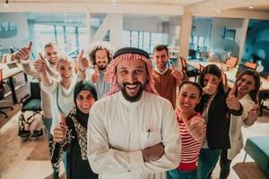 un diverso grupo de exitoso negocio personas en un moderno vaso oficina estar juntos a el parte superior con su árabe líder director foto