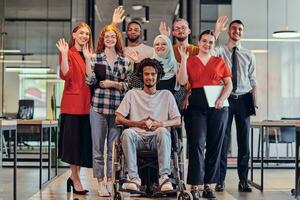 A diverse group of young business people congregates within a modern startup's glass-enclosed office, featuring inclusivity with a person in a wheelchair, an African American young man , and a hijab-clad woman, showcasing a dynamic blend of innovation and photo