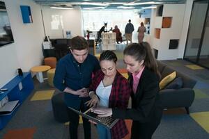 A group of young enthusiastic young business people in modern office. A business woman with a laptop in her hand, in the background a colleagues with crossed arms photo