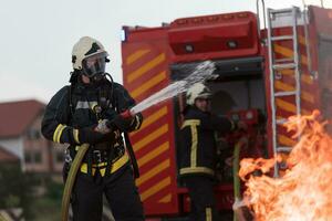 Firefighters using water fog type fire extinguisher to fighting with the fire flame to control fire not to spreading out. Firefighter industrial and public safety concept. photo