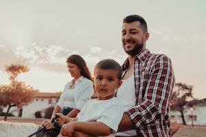 The family spends time with their children while riding horses together on a sandy beach. Selective focus photo