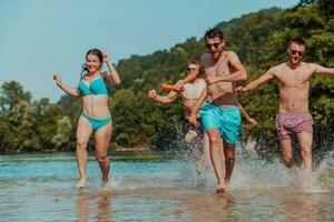 A group of diverse young people having fun together as they run along the river and play water games photo