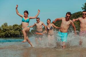 A group of diverse young people having fun together as they run along the river and play water games photo