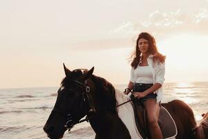 mujer vestida de verano disfruta montando a caballo en una hermosa playa de arena al atardecer. enfoque selectivo foto