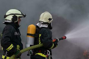 bomberos utilizando agua niebla tipo fuego extintor a luchando con el fuego fuego a controlar fuego no a extensión afuera. bombero industrial y público la seguridad concepto. foto