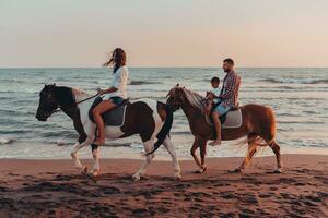 The family spends time with their children while riding horses together on a sandy beach. Selective focus photo