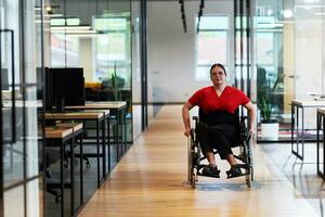 A modern young businesswoman in a wheelchair is surrounded by an inclusive workspace with glass-walled offices, embodying determination and innovation in the business world photo