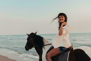 mujer vestida de verano disfruta montando a caballo en una hermosa playa de arena al atardecer. enfoque selectivo foto