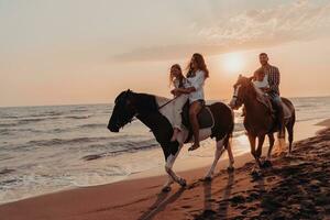 The family spends time with their children while riding horses together on a sandy beach. Selective focus photo