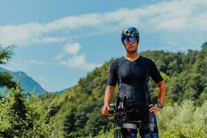 Full length portrait of an active triathlete in sportswear and with a protective helmet riding a bicycle. Selective focus photo