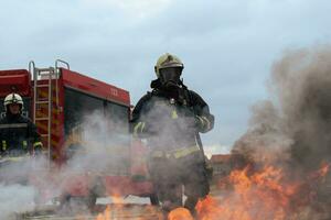 Firefighters using water fog type fire extinguisher to fighting with the fire flame to control fire not to spreading out. Firefighter industrial and public safety concept. photo