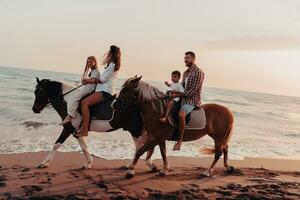 la familia pasa tiempo con sus hijos mientras montan a caballo juntos en una playa de arena. enfoque selectivo foto