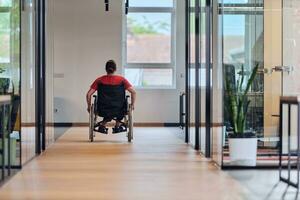 A modern young businesswoman in a wheelchair is surrounded by an inclusive workspace with glass-walled offices, embodying determination and innovation in the business world photo