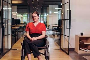 A modern young businesswoman in a wheelchair is surrounded by an inclusive workspace with glass-walled offices, embodying determination and innovation in the business world photo