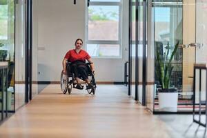 un moderno joven mujer de negocios en un silla de ruedas es rodeado por un inclusivo espacio de trabajo con con paredes de vidrio oficinas, encarnando determinación y innovación en el negocio mundo foto