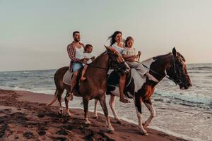 The family spends time with their children while riding horses together on a sandy beach. Selective focus photo