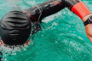 A triathlete in a professional swimming suit trains on the river while preparing for Olympic swimming photo