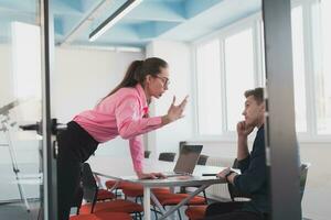 Emotional couple of young colleagues arguing in modern office. African-american business woman shouting at her sad man assistant, copy space, side view photo