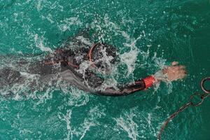 A triathlete in a professional swimming suit trains on the river while preparing for Olympic swimming photo