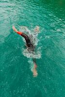 un triatleta en un profesional nadando traje trenes en el río mientras preparando para olímpico nadando foto