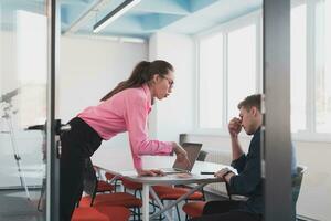 Emotional couple of young colleagues arguing in modern office. Business woman shouting at her sad man assistant, copy space, side view photo