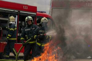 Firefighters fight the fire flame to control fire not to spreading out. Firefighter industrial and public safety concept. Traffic or car accident rescue and help action. photo