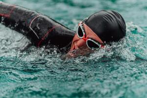 A triathlete in a professional swimming suit trains on the river while preparing for Olympic swimming photo