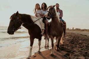 The family spends time with their children while riding horses together on a sandy beach. Selective focus photo