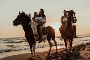 The family spends time with their children while riding horses together on a sandy beach. Selective focus photo