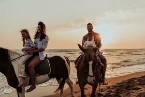 The family spends time with their children while riding horses together on a sandy beach. Selective focus photo