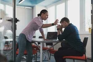 Emotional couple of young colleagues arguing in modern office. African-american business woman shouting at her sad man assistant, copy space, side view photo