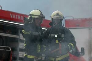 bomberos utilizando agua niebla tipo fuego extintor a luchando con el fuego fuego a controlar fuego no a extensión afuera. bombero industrial y público la seguridad concepto. foto