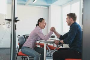 businesspeople, rivalry and people concept - businesswoman and businessman arm wrestling during corporate meeting in modern bright open space coworking startup business office. photo