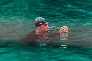 A triathlete in a professional swimming suit trains on the river while preparing for Olympic swimming photo