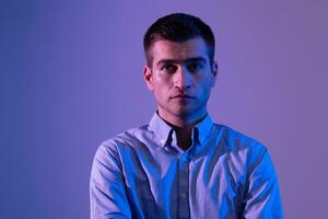 A man in a shirt poses on a dark multicolored neon background photo