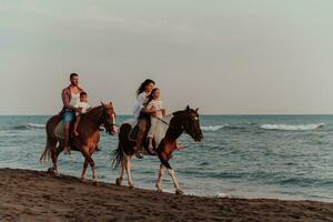 The family spends time with their children while riding horses together on a sandy beach. Selective focus photo