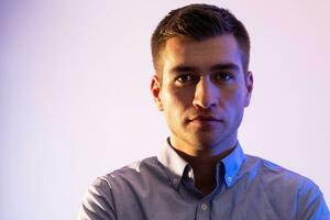 A man in a shirt poses on a dark multicolored neon background photo