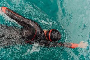 A triathlete in a professional swimming suit trains on the river while preparing for Olympic swimming photo