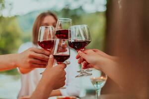 grupo de contento amigos tostado rojo vino vaso mientras teniendo picnic francés cena fiesta al aire libre durante verano fiesta vacaciones cerca el río a hermosa naturaleza foto