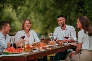 Group of happy friends having picnic french dinner party outdoor during summer holiday vacation near the river at beautiful nature photo