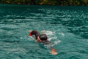 A triathlete in a professional swimming suit trains on the river while preparing for Olympic swimming photo