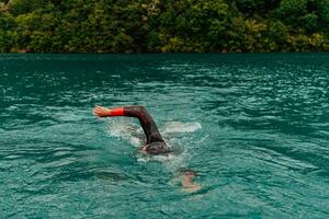 un triatleta en un profesional nadando traje trenes en el río mientras preparando para olímpico nadando foto